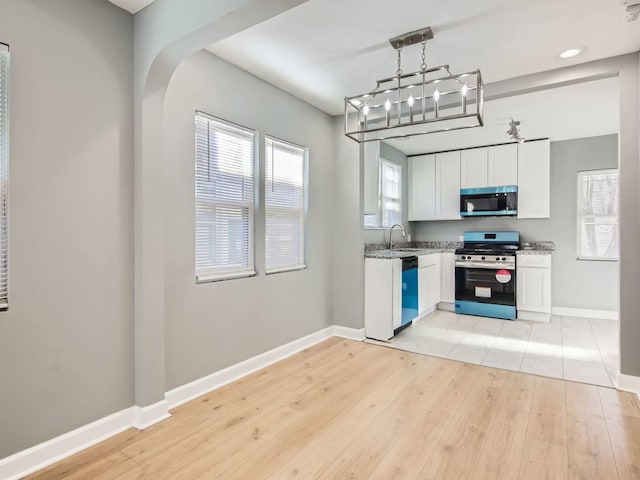 kitchen featuring sink, light hardwood / wood-style flooring, stainless steel appliances, white cabinets, and decorative light fixtures