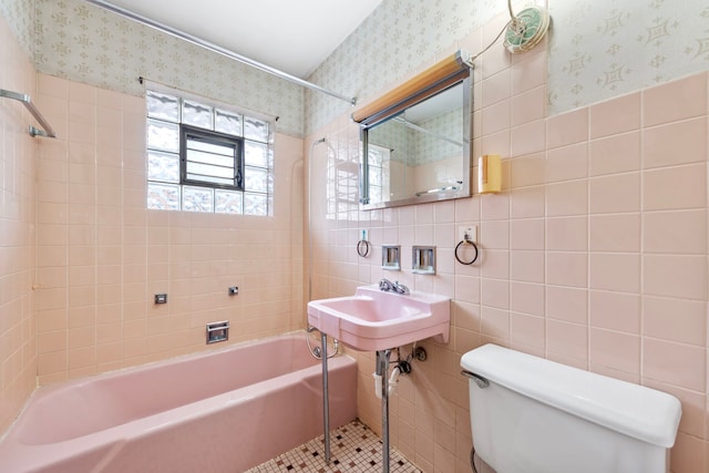 full bathroom with toilet, tiled shower / bath combo, tile walls, tile patterned flooring, and sink