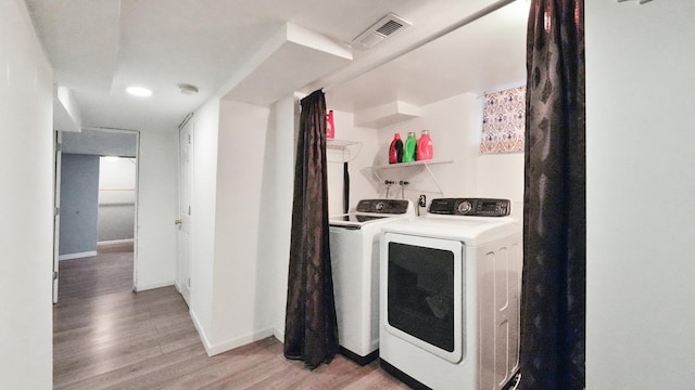 clothes washing area featuring independent washer and dryer and light hardwood / wood-style flooring