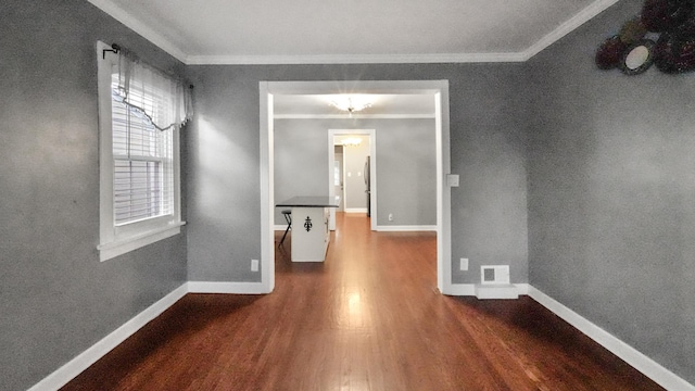 empty room featuring an inviting chandelier, crown molding, and hardwood / wood-style flooring