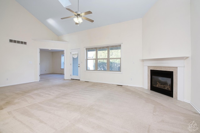 unfurnished living room with high vaulted ceiling, ceiling fan, light carpet, and a tiled fireplace