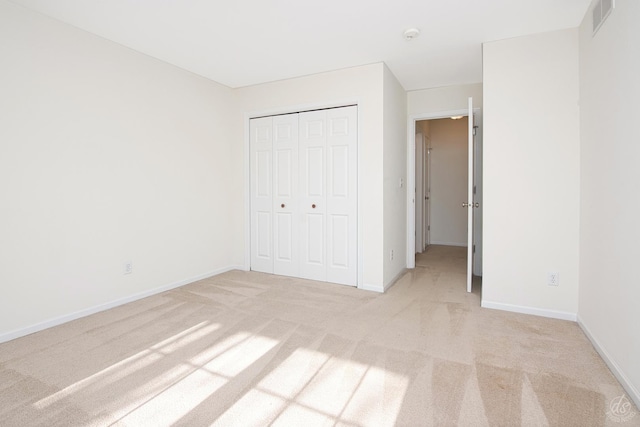 unfurnished bedroom featuring a closet and light colored carpet