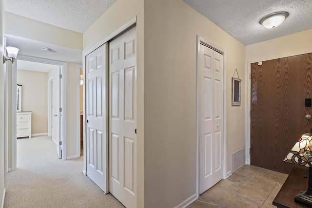 hall featuring light colored carpet and a textured ceiling