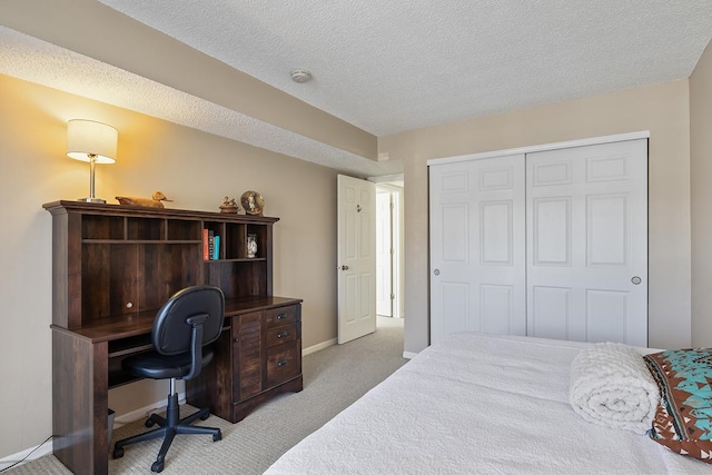 bedroom featuring light colored carpet, a textured ceiling, and a closet