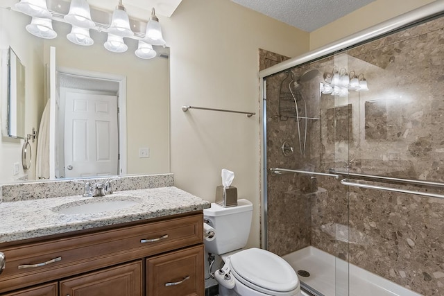 bathroom with vanity, toilet, a textured ceiling, and walk in shower