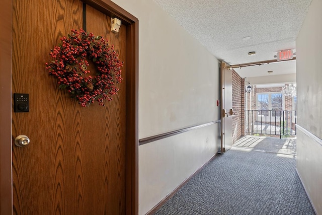 corridor featuring carpet flooring and a textured ceiling