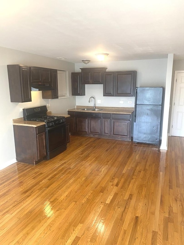 kitchen featuring sink, light hardwood / wood-style flooring, dark brown cabinetry, and black appliances