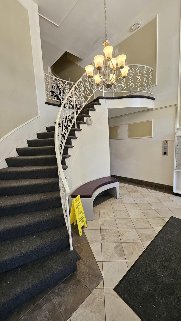 staircase with tile patterned flooring and a notable chandelier