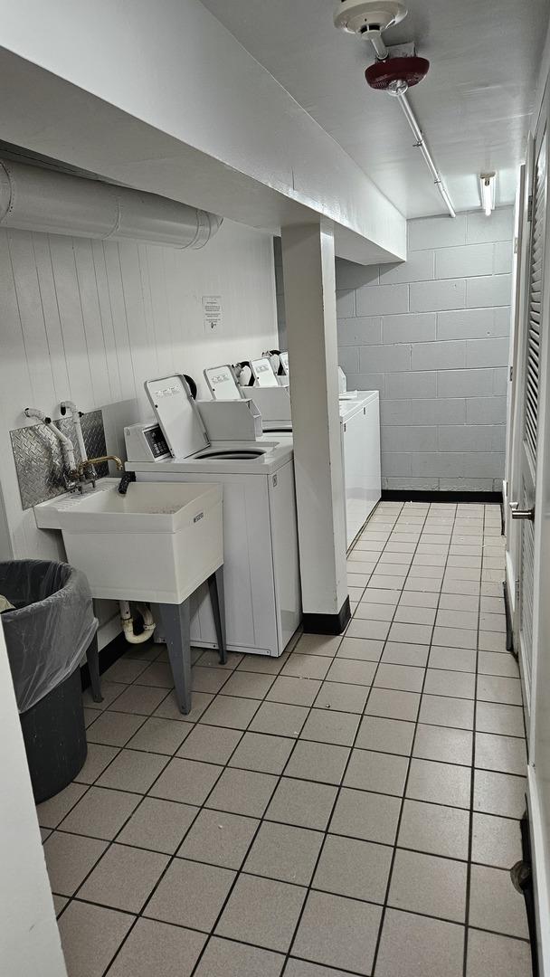 washroom featuring light tile patterned flooring, washing machine and clothes dryer, and sink