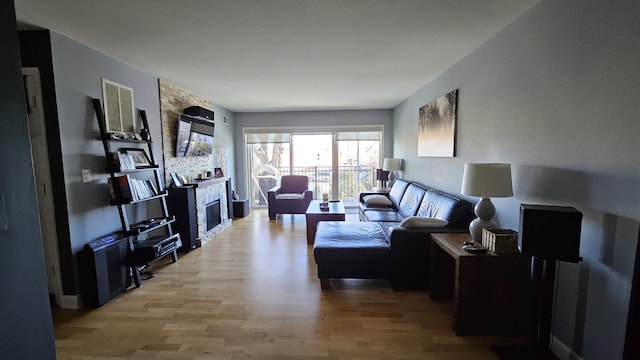 living room featuring light hardwood / wood-style floors and a stone fireplace