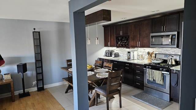 kitchen featuring appliances with stainless steel finishes, light tile patterned floors, tasteful backsplash, and dark brown cabinetry