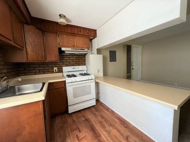 kitchen with gas range gas stove, kitchen peninsula, decorative backsplash, dark wood-type flooring, and sink