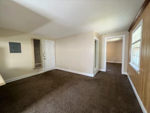 carpeted empty room with wooden walls and electric panel