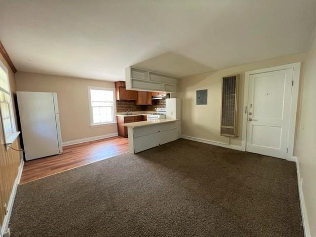 kitchen featuring tasteful backsplash, kitchen peninsula, electric panel, stove, and range hood