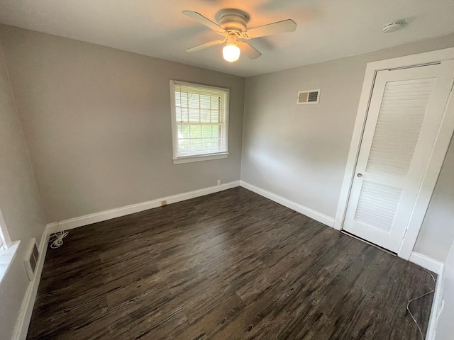 unfurnished bedroom with ceiling fan, dark hardwood / wood-style flooring, and a closet