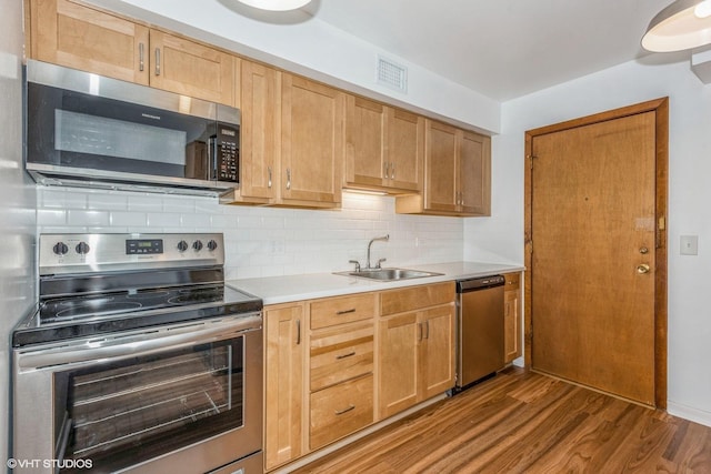 kitchen with sink, appliances with stainless steel finishes, dark hardwood / wood-style floors, and tasteful backsplash