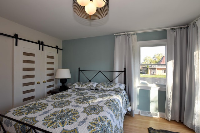 bedroom featuring a barn door and light wood-type flooring