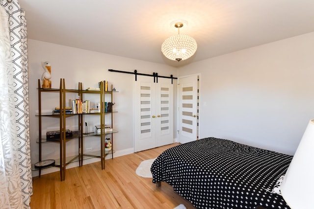 bedroom with wood-type flooring and a barn door