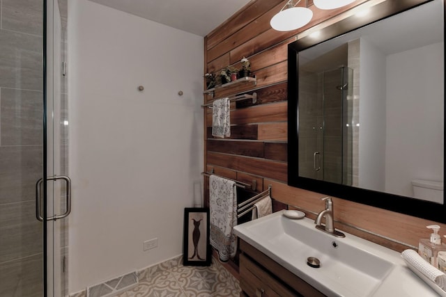 bathroom featuring tile patterned floors, vanity, a shower with shower door, and wooden walls