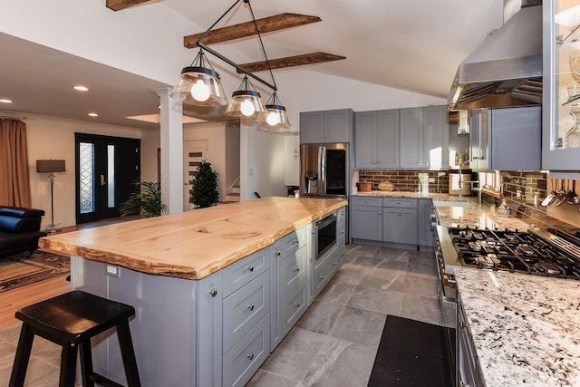 kitchen with ventilation hood, lofted ceiling with beams, decorative backsplash, gray cabinets, and butcher block counters