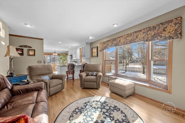 living room featuring light wood-type flooring, ceiling fan, and a healthy amount of sunlight