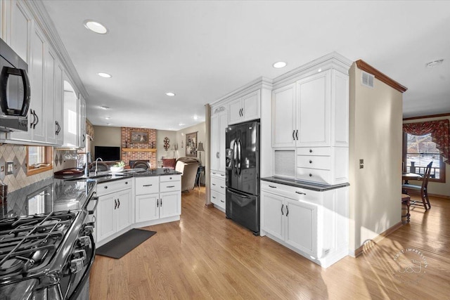 kitchen featuring black appliances, light hardwood / wood-style floors, kitchen peninsula, decorative backsplash, and white cabinetry