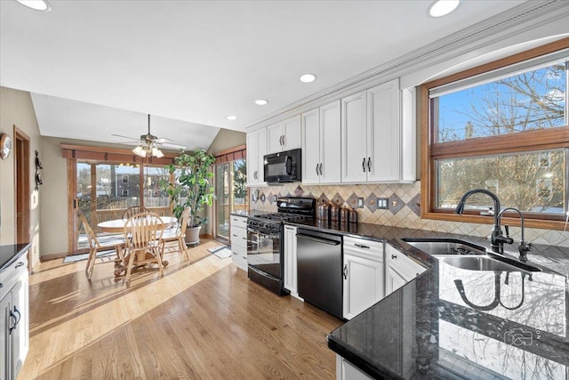 kitchen featuring sink, white cabinetry, lofted ceiling, decorative backsplash, and black appliances