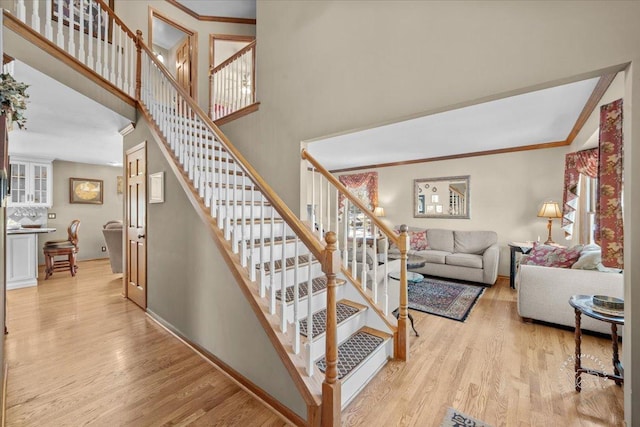 stairs featuring ornamental molding, hardwood / wood-style floors, and a towering ceiling