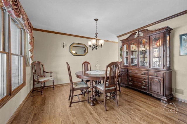 dining area featuring a chandelier, light wood-type flooring, and crown molding