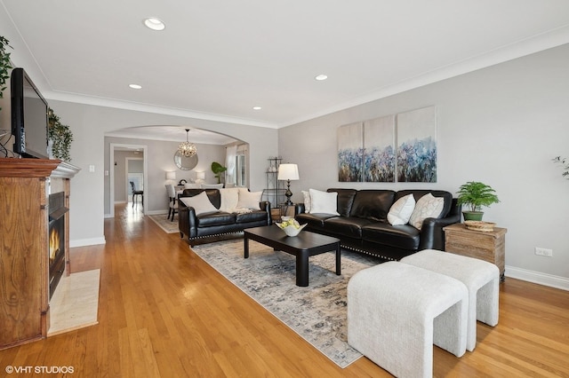 living room with ornamental molding, a notable chandelier, and light hardwood / wood-style flooring