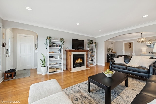 living room with an inviting chandelier, ornamental molding, wood-type flooring, and a high end fireplace