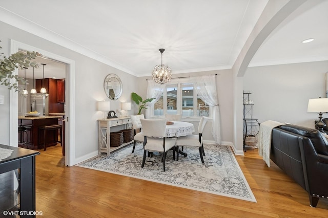 dining room with crown molding, light hardwood / wood-style floors, and a chandelier