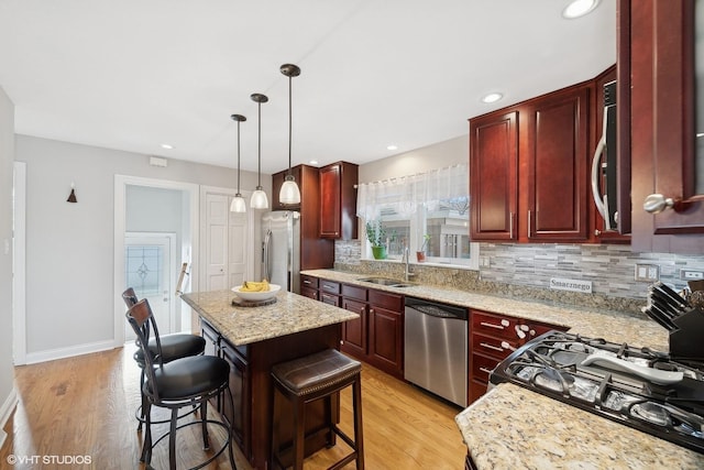 kitchen featuring sink, tasteful backsplash, a center island, appliances with stainless steel finishes, and a kitchen breakfast bar