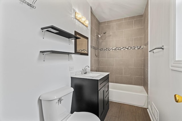 full bathroom with hardwood / wood-style floors, vanity, tiled shower / bath combo, and toilet