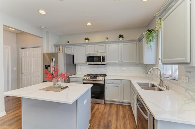 kitchen featuring stainless steel appliances, backsplash, a center island, light stone countertops, and sink