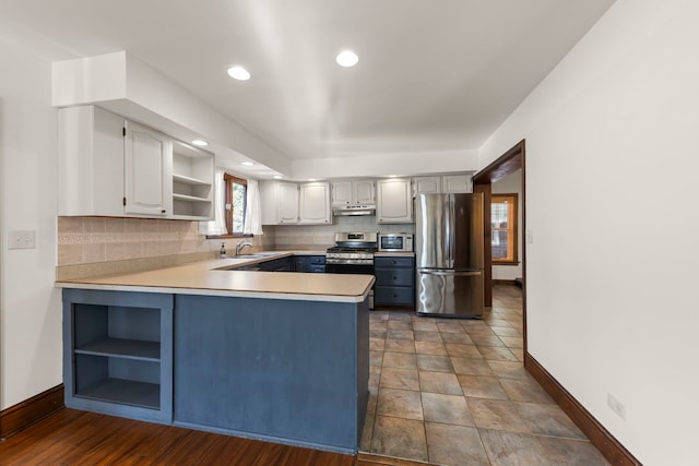 kitchen featuring kitchen peninsula, stainless steel appliances, decorative backsplash, white cabinetry, and sink