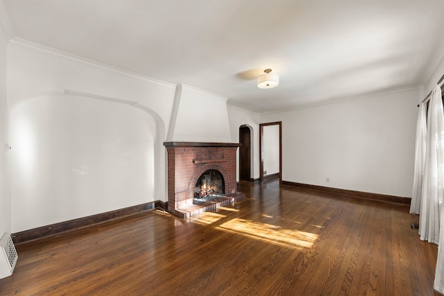 unfurnished living room with a brick fireplace, dark wood-type flooring, and crown molding