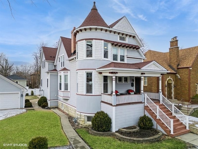 victorian house with a garage, covered porch, and a front lawn