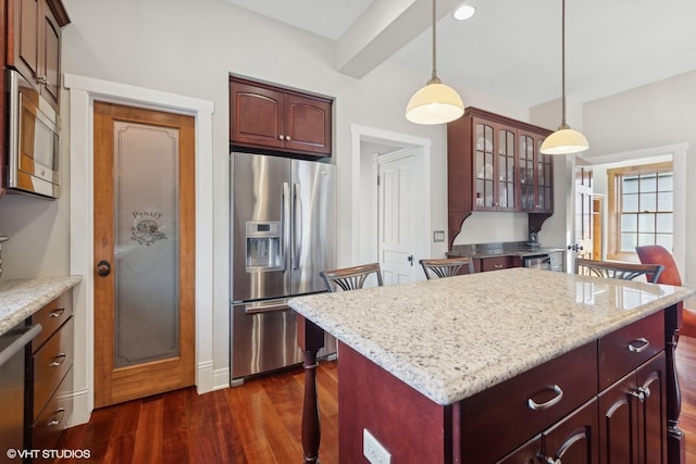 kitchen featuring decorative light fixtures, a center island, appliances with stainless steel finishes, dark hardwood / wood-style flooring, and beamed ceiling