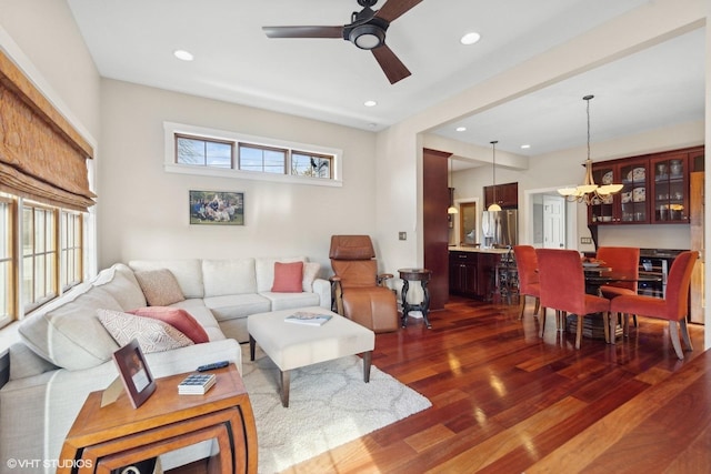 living room with dark wood-type flooring and ceiling fan with notable chandelier