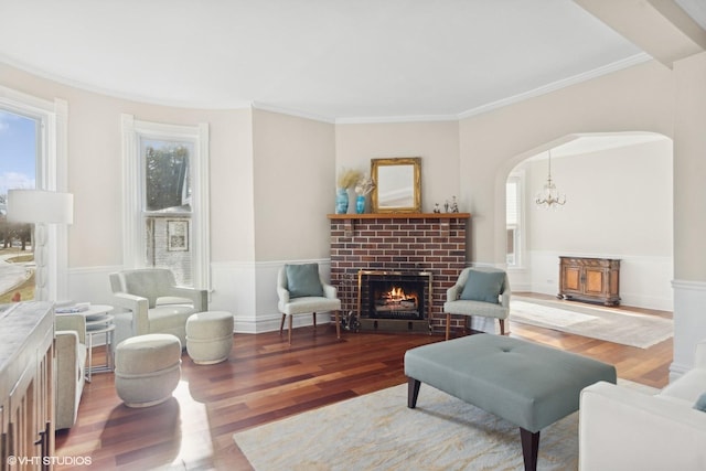 living room featuring an inviting chandelier, hardwood / wood-style floors, crown molding, and a fireplace