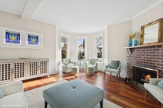 living room with hardwood / wood-style flooring, ornamental molding, a brick fireplace, and beam ceiling