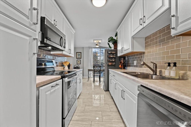 kitchen featuring sink, stainless steel appliances, tasteful backsplash, and white cabinetry