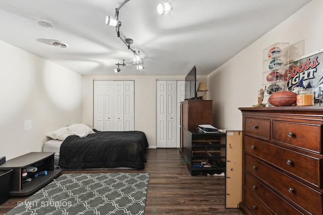 bedroom with dark wood-type flooring and two closets