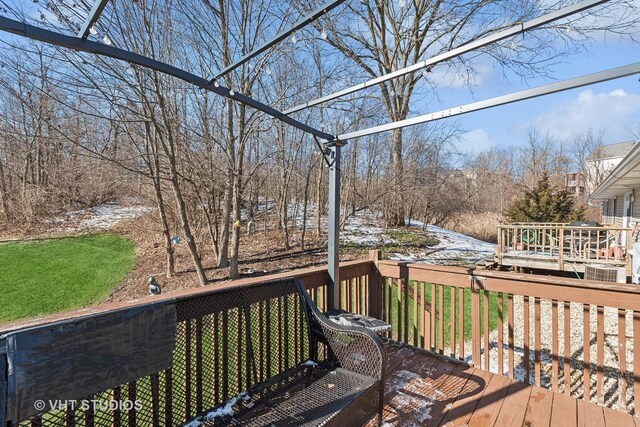 rear view of property with a deck, a yard, and central AC