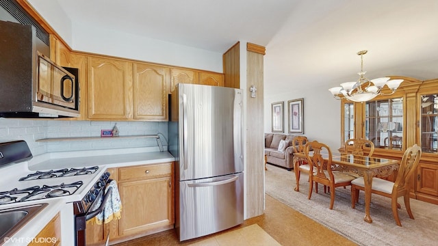 kitchen featuring pendant lighting, backsplash, white range with gas stovetop, stainless steel refrigerator, and a chandelier