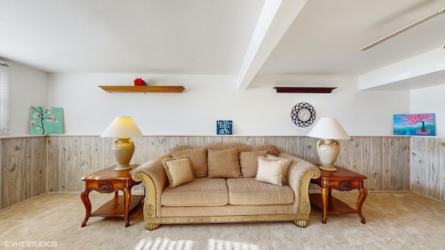 carpeted living room with beamed ceiling and wooden walls