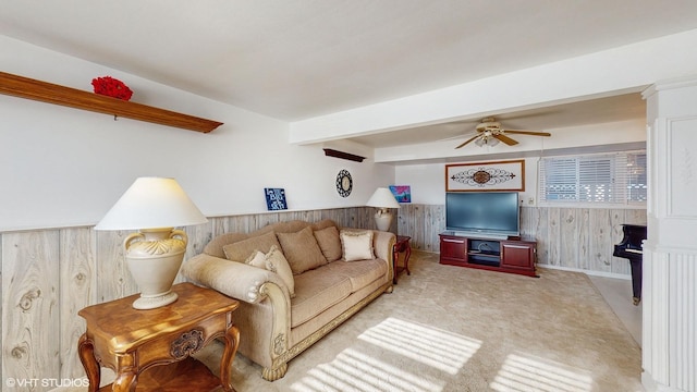 living room featuring light carpet, ceiling fan, and wood walls