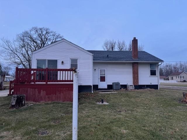 back of property with cooling unit, a deck, and a yard