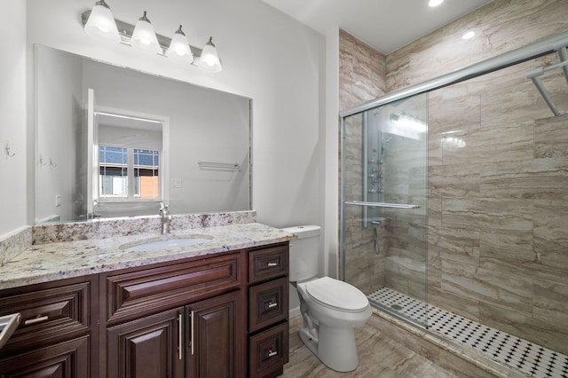 bathroom with vanity, toilet, and a shower with door